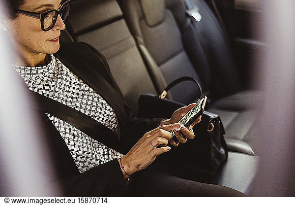 Female entrepreneur using device screen while sitting in car