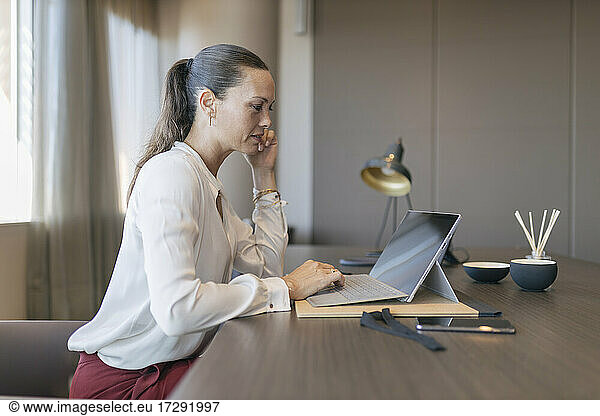 Female entrepreneur using laptop while sitting at desk in office