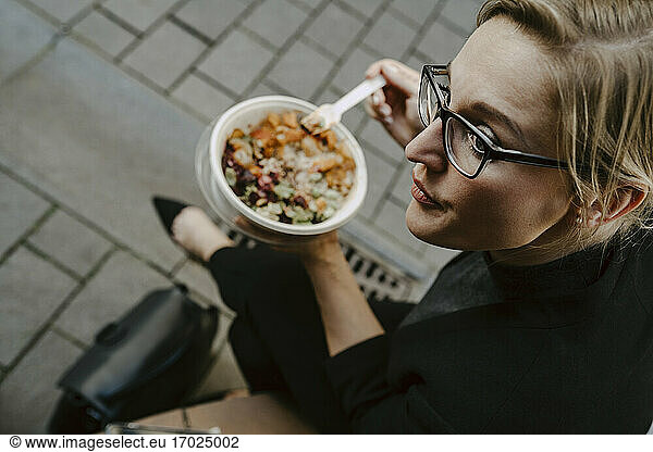 Female entrepreneur with salad bowl looking away