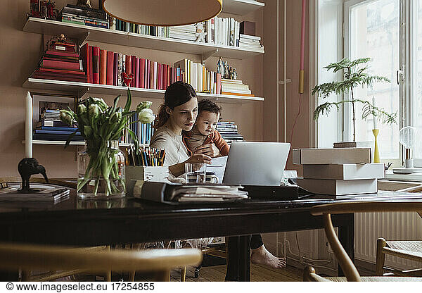 Female entrepreneur with toddler son working in home office