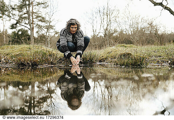 Female explorer washing hands in lake at forest