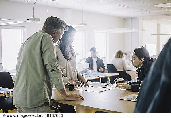 Female fashion designer discussing with colleagues at workshop