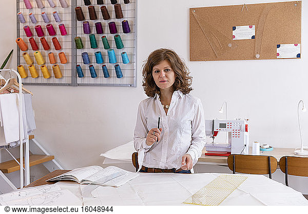 Female fashion designer standing at workbench in studio