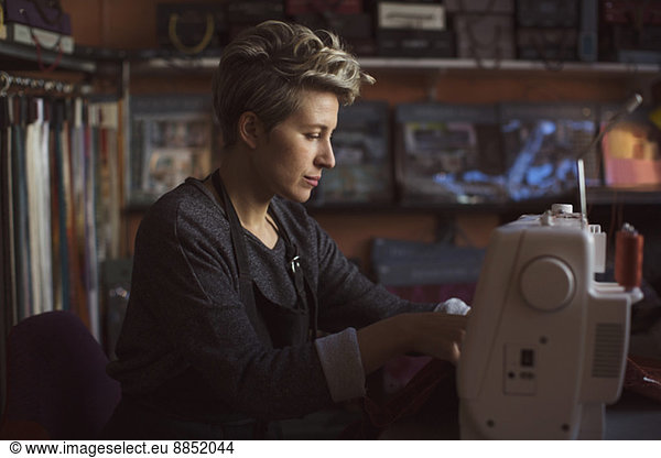 Female fashion designer using sewing machine in studio