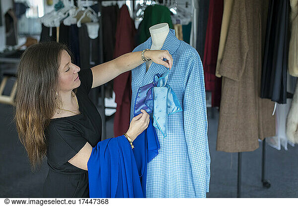 Female fashion entrepreneur styles a blue shirt in her design studio