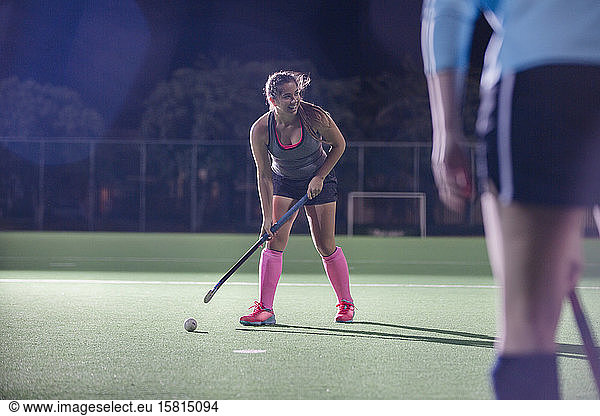 Female field hockey player hitting the ball with hockey stick on field