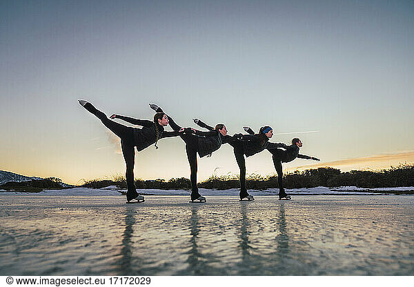 Female figure skaters practicing on frozen lake at dusk