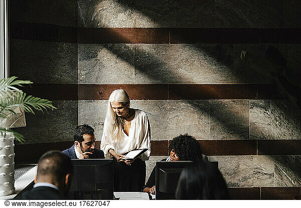 Female financial advisor discussing over document with colleagues at law office