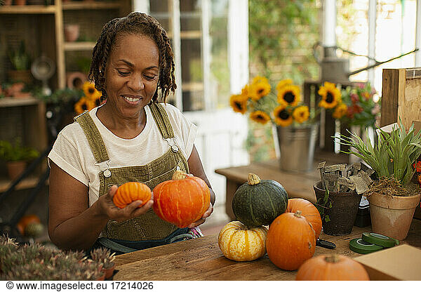 Female florist arranging autumn pumpkins in shop