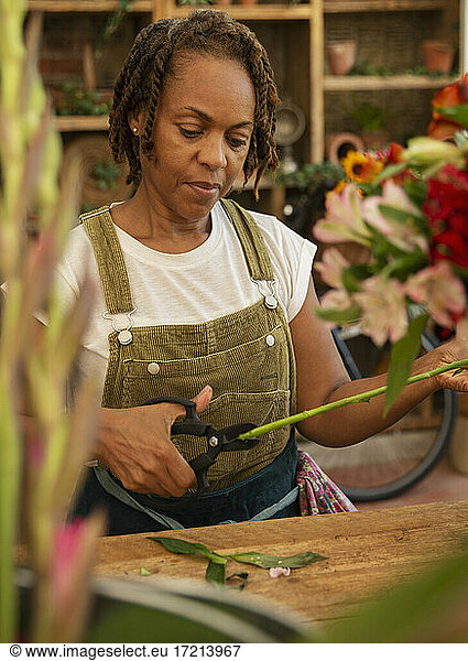 Female florist trimming flower stem in shop