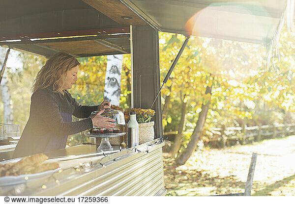 Female food truck owner arranging pastries in sunny autumn park