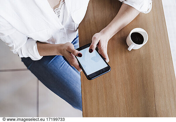 Female freelance worker using smart phone while sitting at desk in office