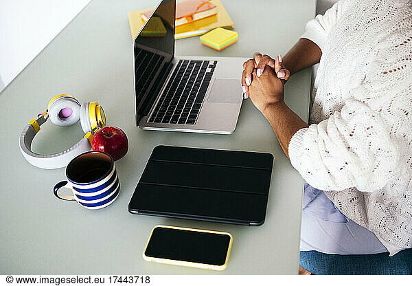 Female freelancer with hands clasped at desk