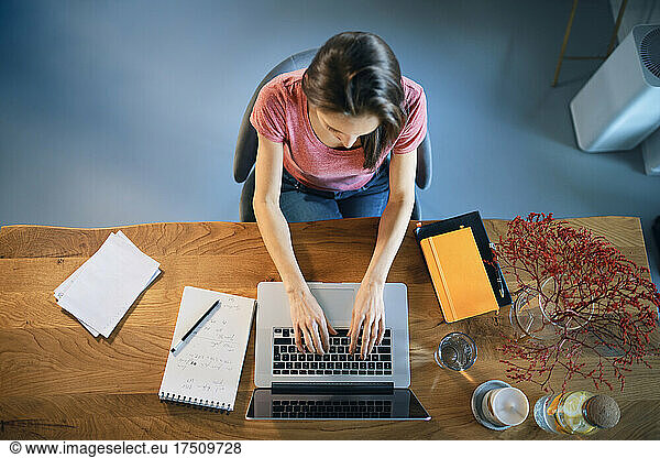 Female freelancer working over laptop on desk while sitting in home office