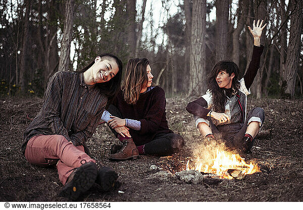 female friends chatting around campfire in forrest