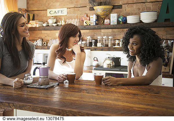 Female friends drinking coffee and enjoying in kitchen at home
