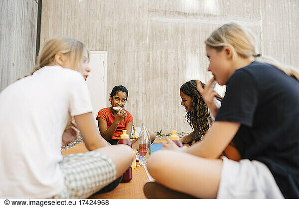 Female friends eating food at sports court