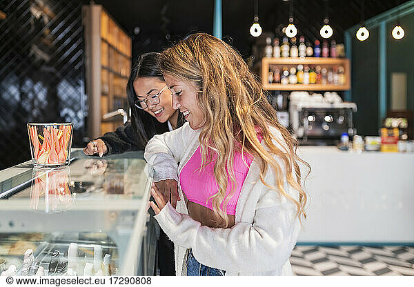 Female friends looking at ice cream displayed in store