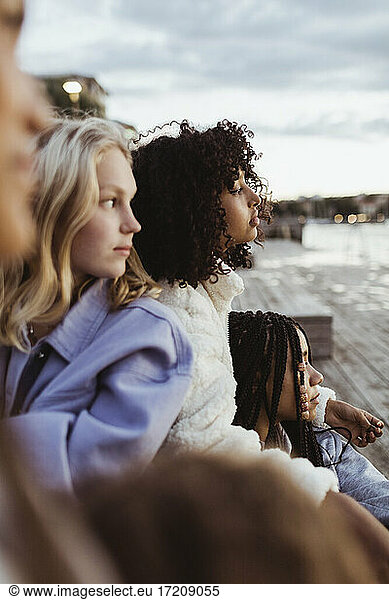 Female friends looking while sitting on pier