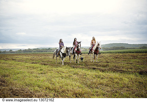 Female friends riding on horses against sky