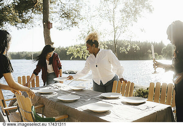 Female friends setting table for dinner party on sunny day