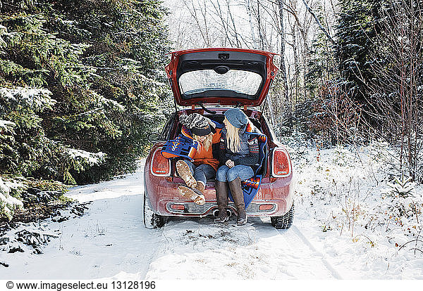 Female friends sitting in car trunk at Algonquin Provincial Park during winter