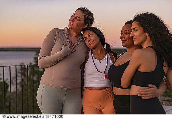 Female friends standing with each other at sunset