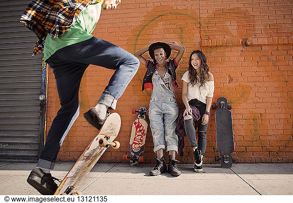 Female friends watching man performing skateboard stunt