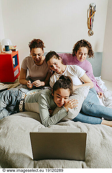 Female friends watching movie together on laptop at home