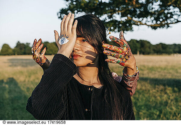 Female friends with painted hands at park during sunset