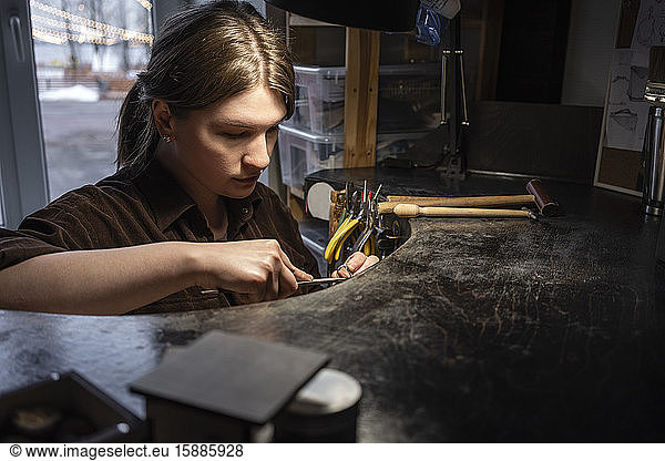 Female goldsmith working on her workbench in the workshop