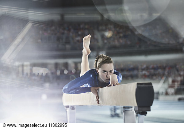 Female gymnast practicing on balance beam in arena