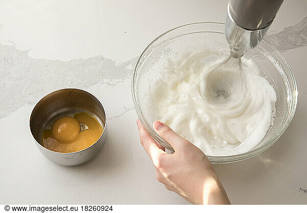 female hand using electric mixer to make whipped cream
