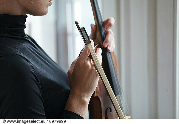 female hands holding alt violin with musician bow  close up detail