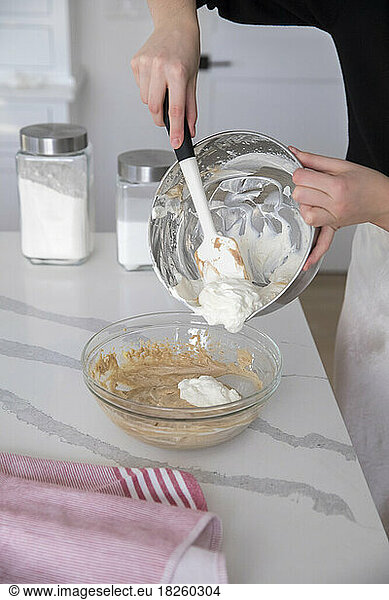 female hands using spatula to take make whipped cream out of bowl