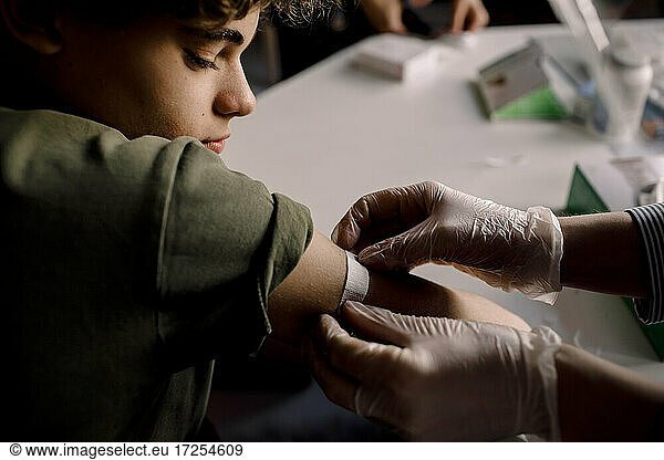 Female healthcare worker applying bandage to boy's arm