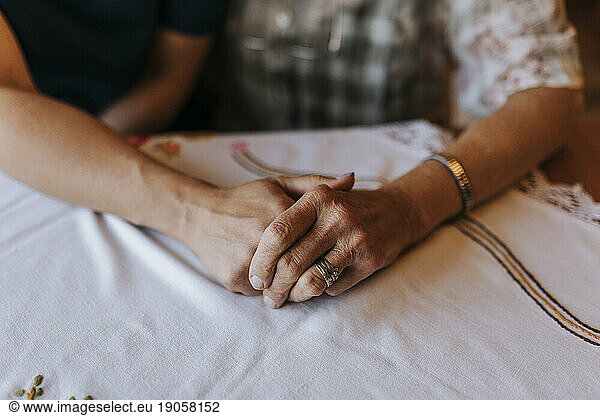 Female healthcare worker holding wrinkled hand of senior woman at home