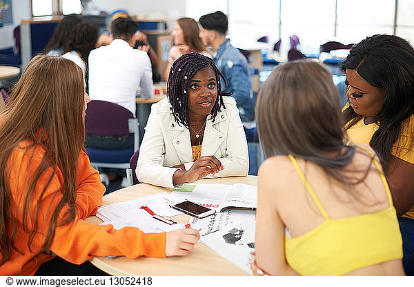 Female higher education students discussing project in college classroom