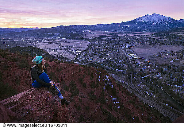 Female hiker looking at Mount Sopris from mushroom rock during sunrise