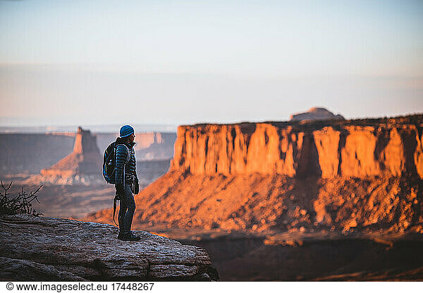female hiker looks out over Canyonlands National Park at sunset  Utah