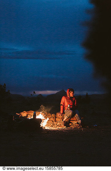 female hiker sitting around a campfire in the desert of utah near moab