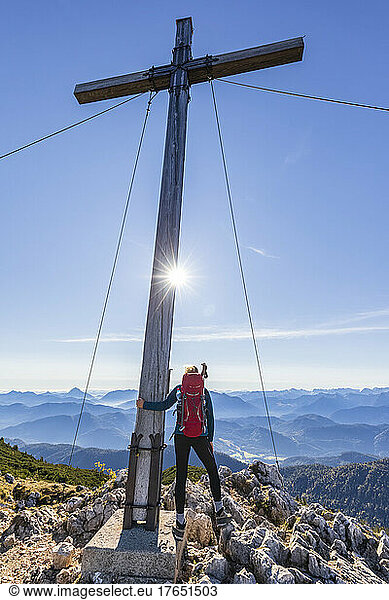 Female hiker standing beside summit cross on Benediktenwand