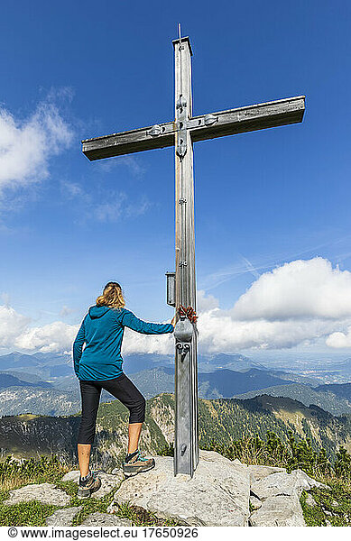 Female hiker standing by summit cross of Demeljoch mountain