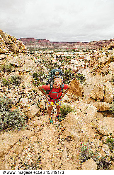 female hiker with hands on hips looks at camera while hiking utah