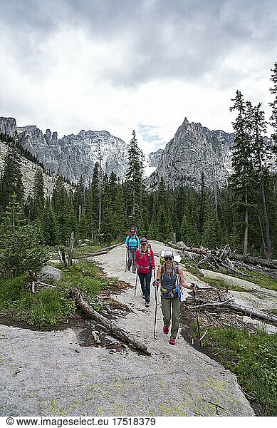 Female hikers smile on the trail in front of Lone Eagle Peak