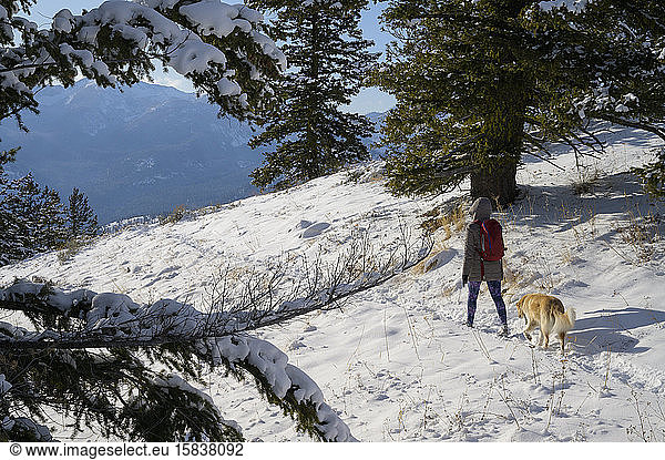 Female Hiking Through Snow With Dog
