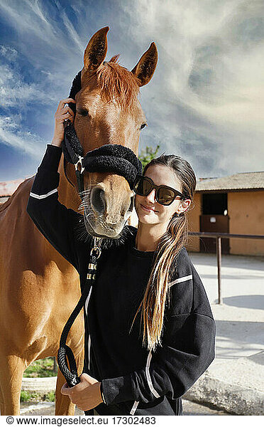 female horse racing jockey with her horse kissing  caressing and caring for him