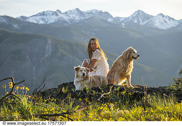 Female in a dress posing with dogs with mountain views