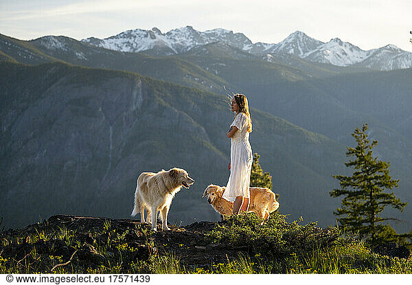 Female in a dress posing with dogs with mountain views