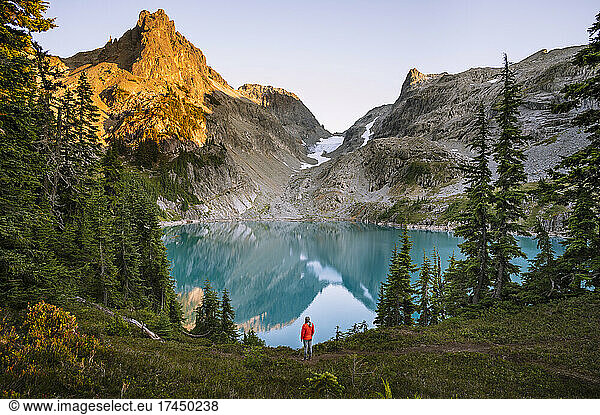 Female In Red Jacket Next To Gorgeous Blue Alpine Lake At Sunset